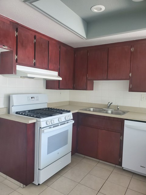A kitchen with a white stove and brown cabinets.