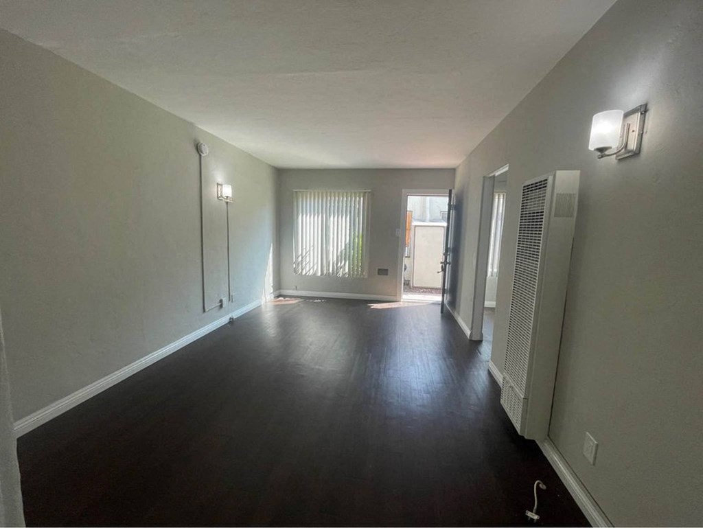 an empty living room with a hard wood floor and white walls