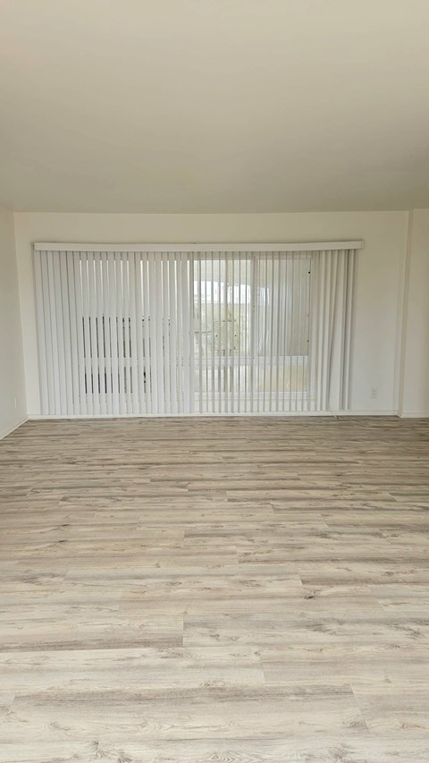A room with wooden flooring and white blinds on the window.