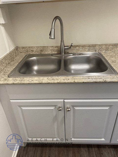a kitchen with a stainless steel sink and white cabinets