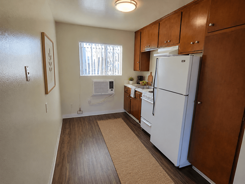 A kitchen with a white refrigerator and wooden cabinets.