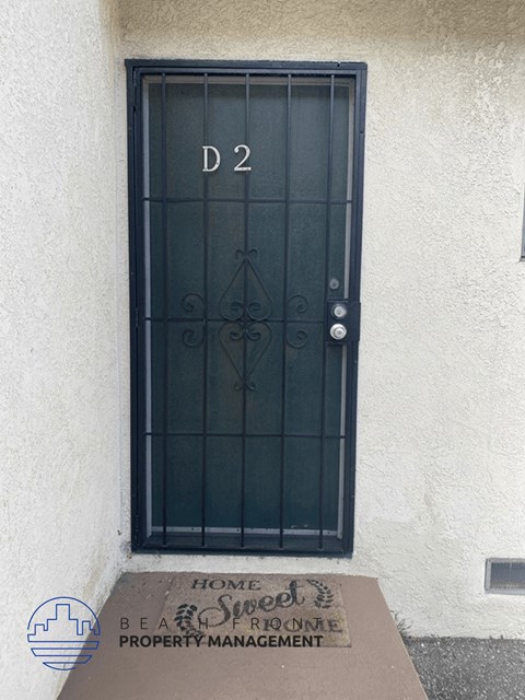 a black door on a white building with a sign in front of it