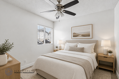 A well-lit bedroom with a large bed, a ceiling fan, and a small table with a plant on it.