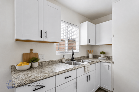 A kitchen with white cabinets and a granite countertop.