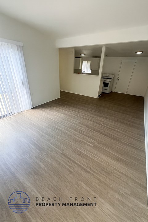 A spacious room with wooden flooring and a large window.