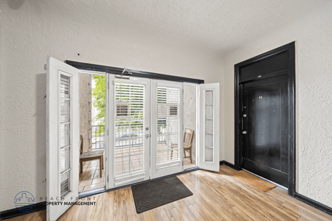 A room with a black door and a wooden floor.