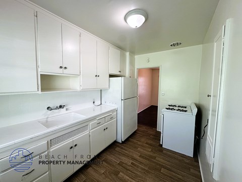 A kitchen with white cabinets and a white fridge.