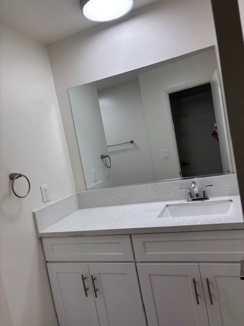 A bathroom with a sink, mirror, and cabinets.