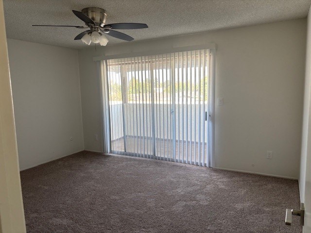 A room with a ceiling fan and carpeted floor.