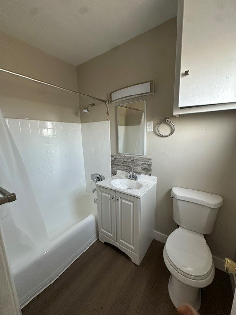 A white toilet sits next to a white sink in a small bathroom.