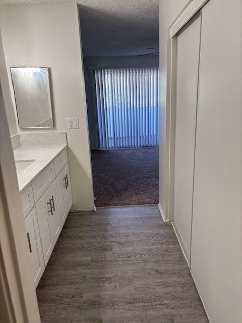 A hallway with a white cabinet and a mirror on the left side.