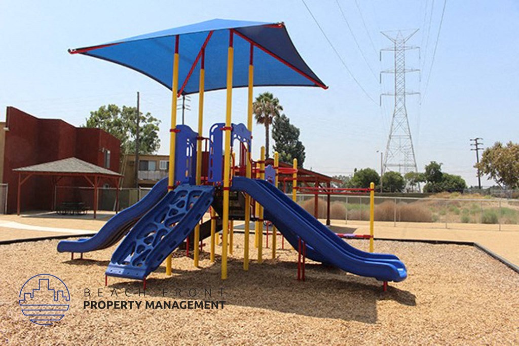 a playground with two slides and a umbrella