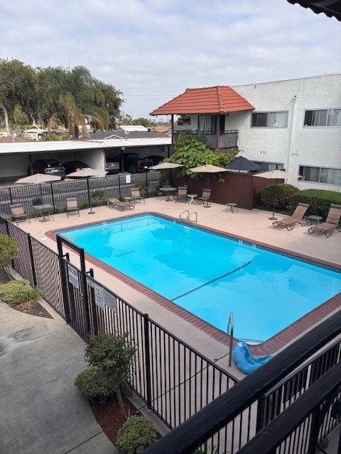 A black fence surrounds a blue swimming pool.