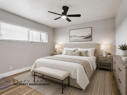 A well-lit bedroom with a large bed, a bench, and a ceiling fan.