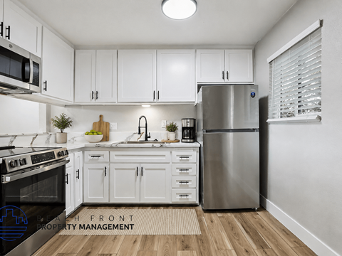 A modern kitchen with white cabinets and stainless steel appliances.