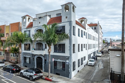 A street view of a building with cars parked in front.