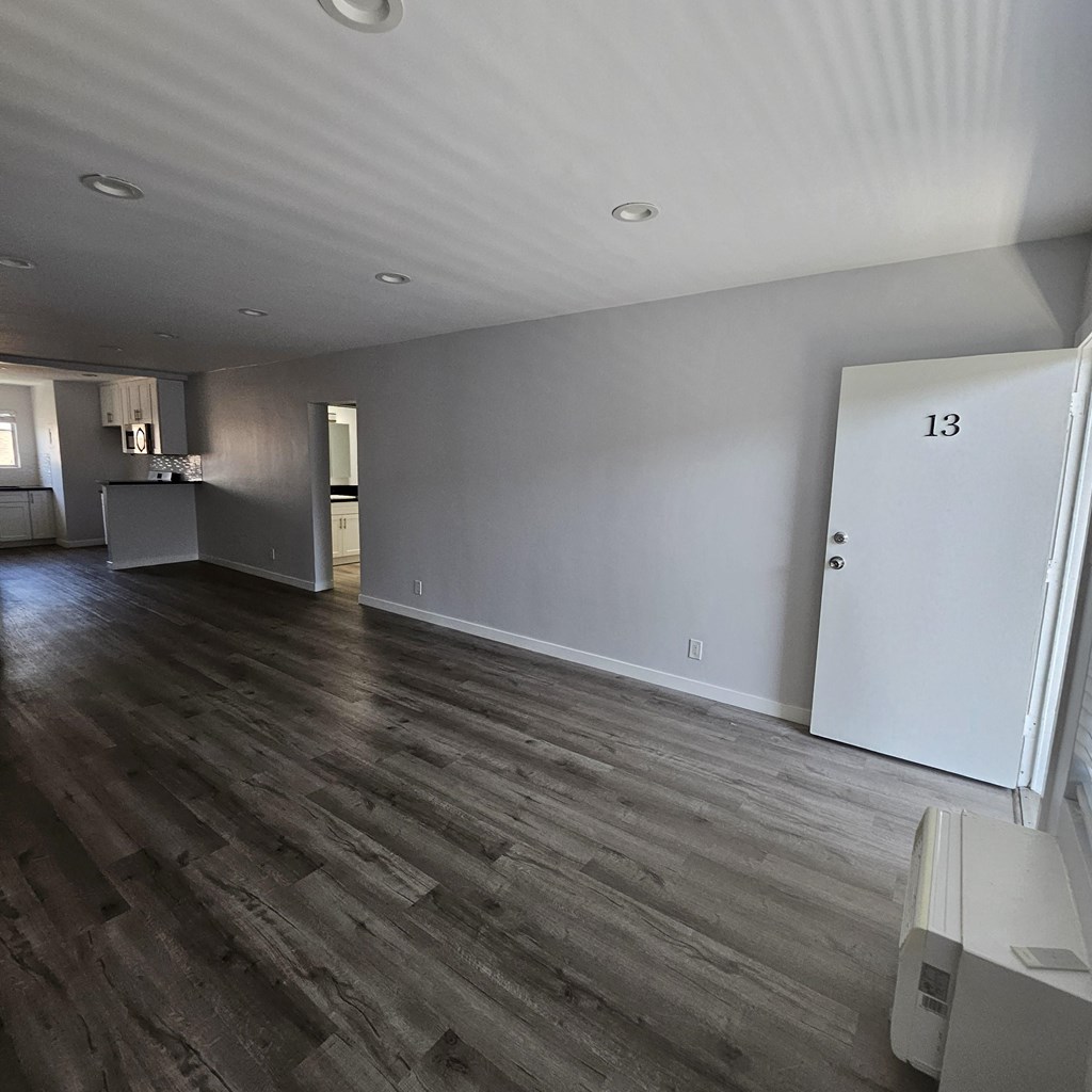 an empty living room with wood flooring and white walls