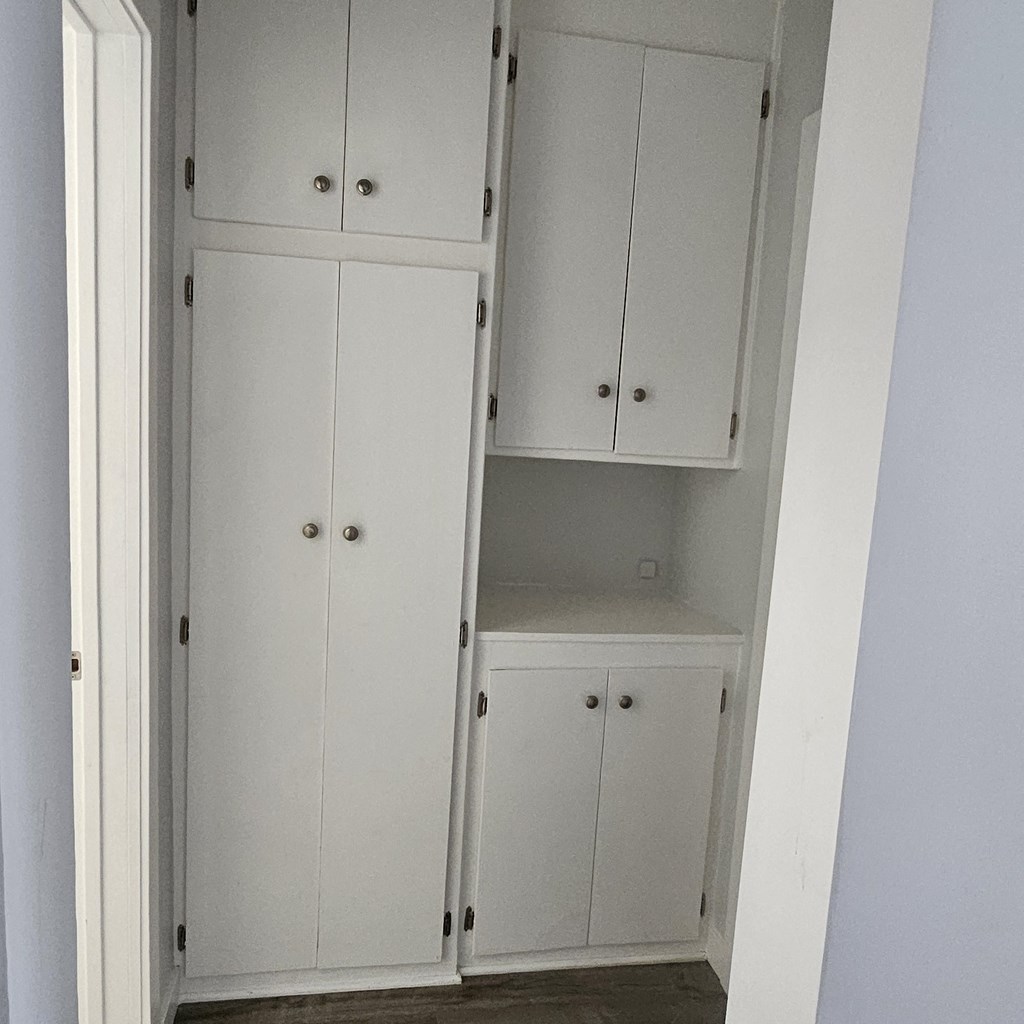 a closet with white cabinets and drawers and