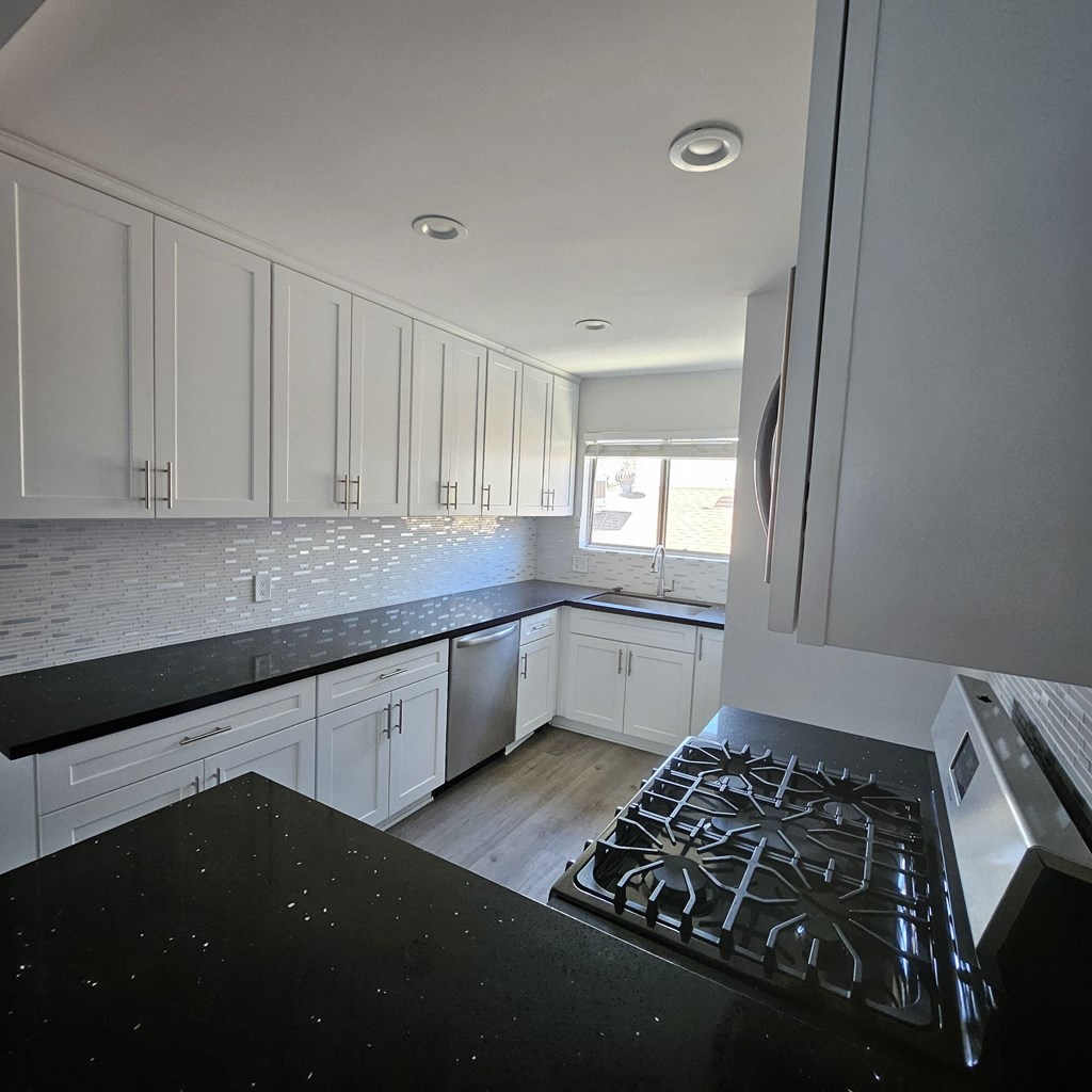 a view of a kitchen with white cabinets and a stove