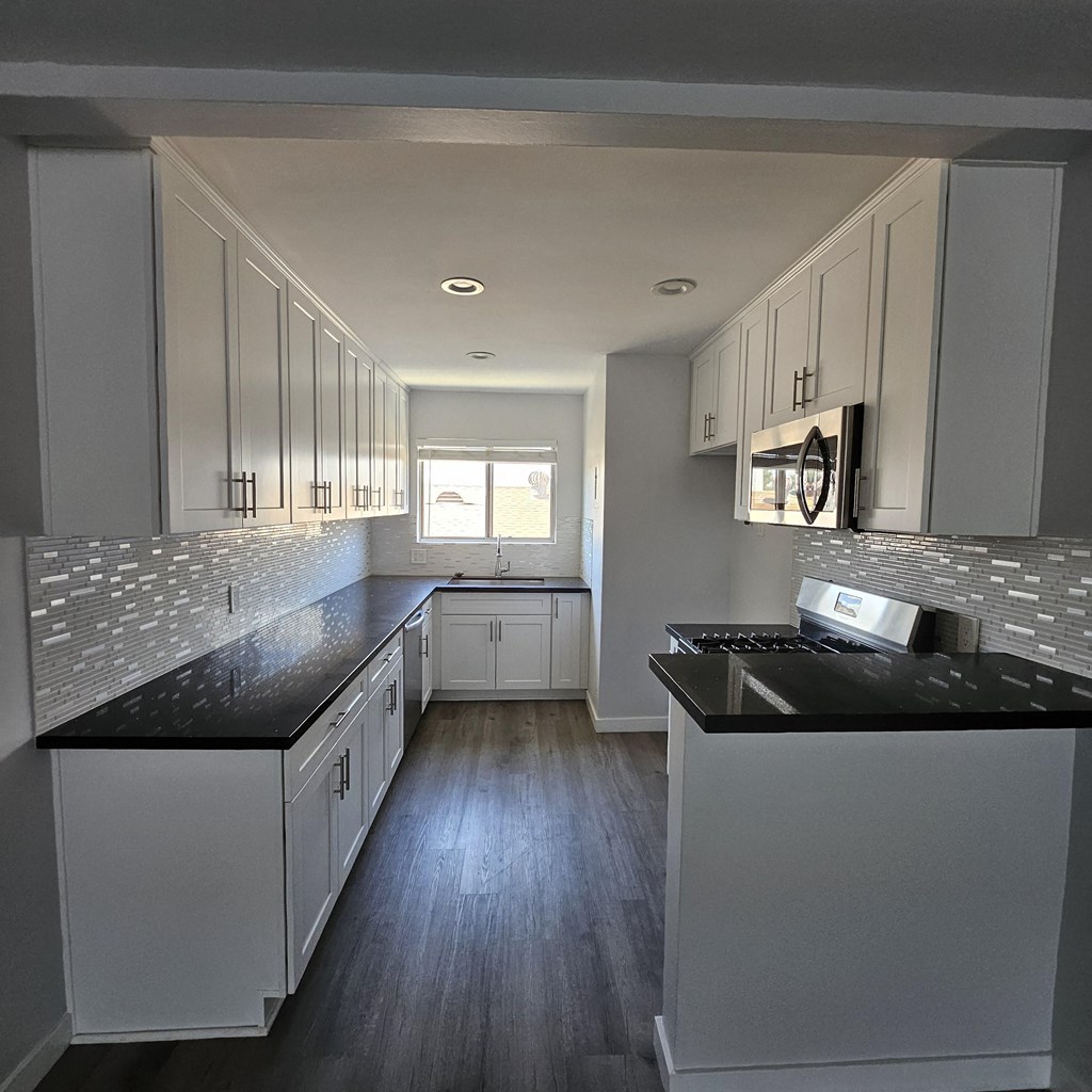 a view of a kitchen with white cabinets and black counter tops