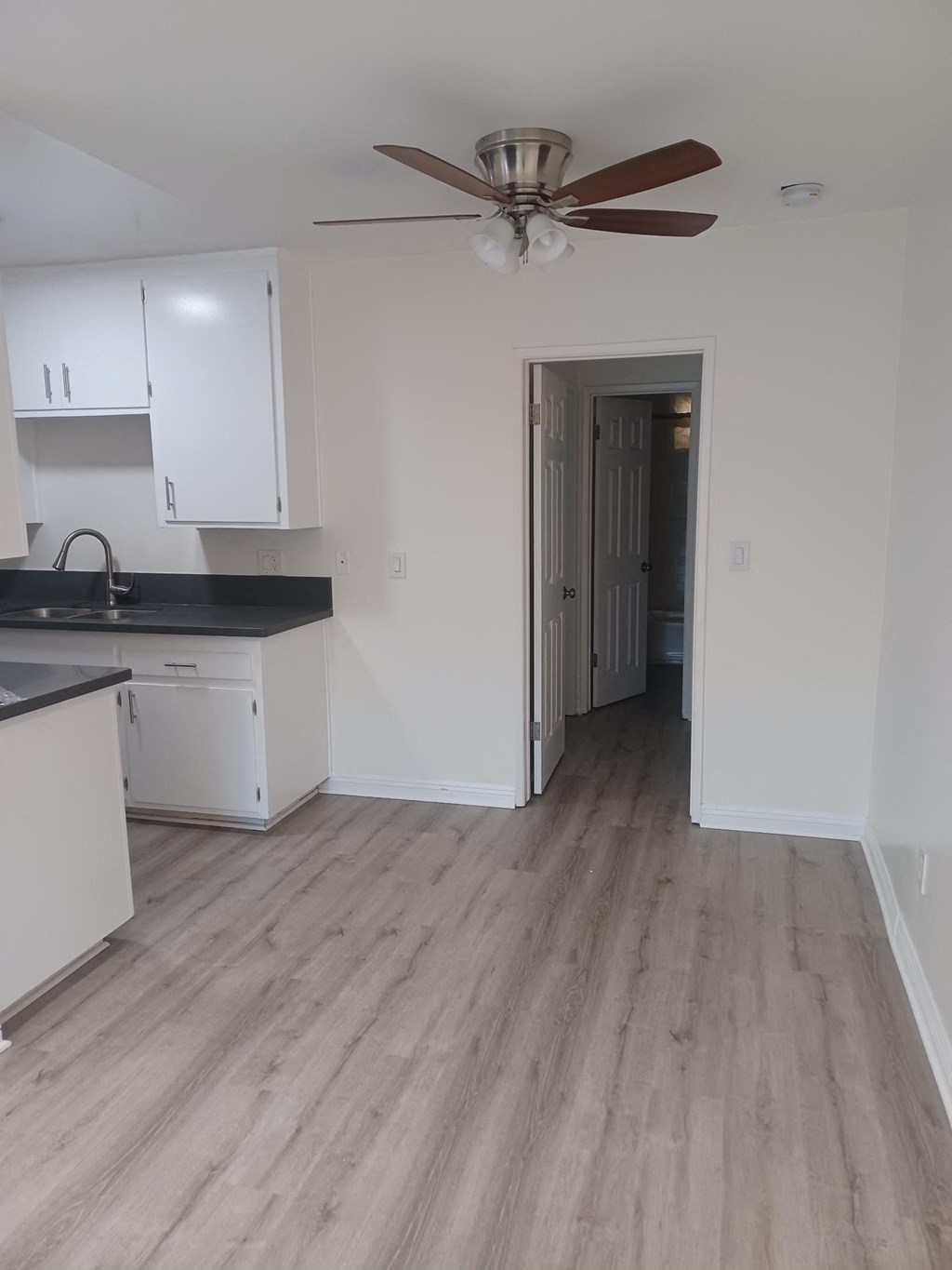 an empty kitchen with white cabinets and a ceiling fan