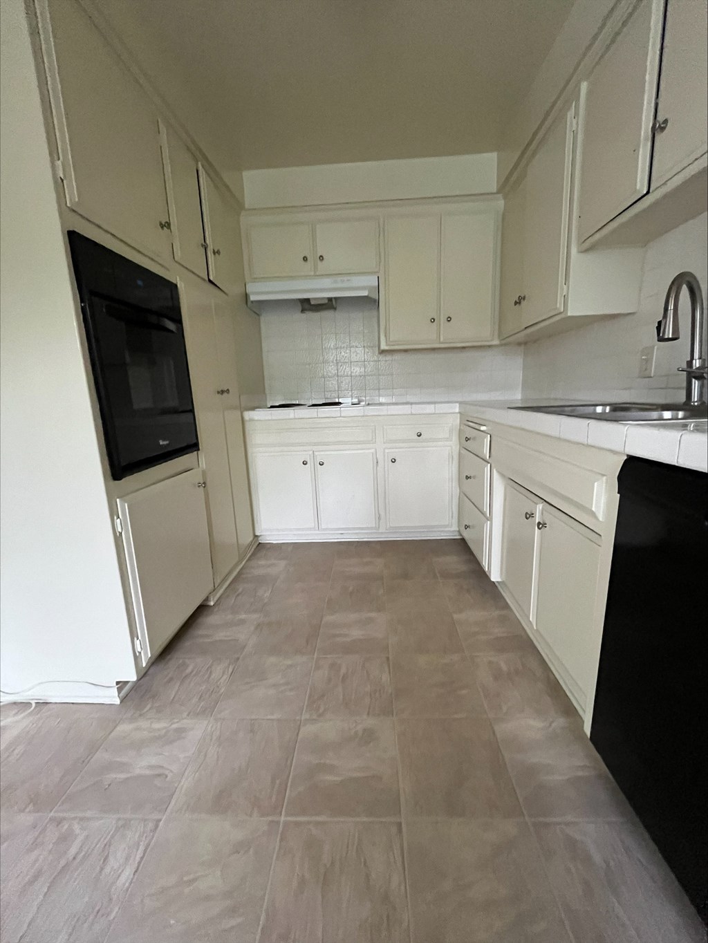 an empty kitchen with white cabinets and black appliances