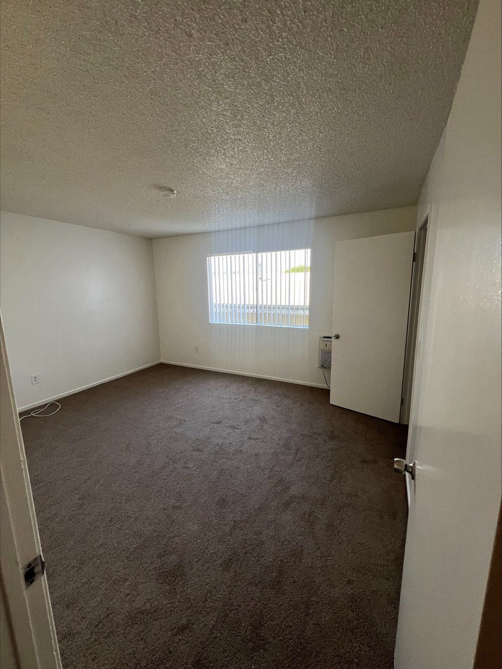 an empty living room with a window and a door