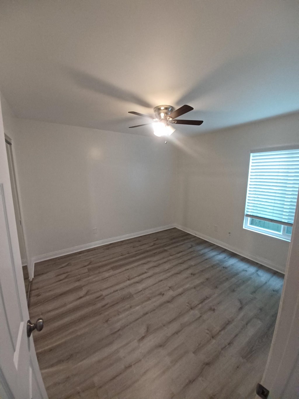 an empty room with a ceiling fan and a window