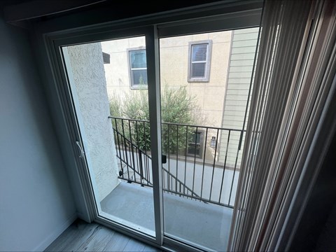 A balcony with a metal railing and a glass door leading to a building.