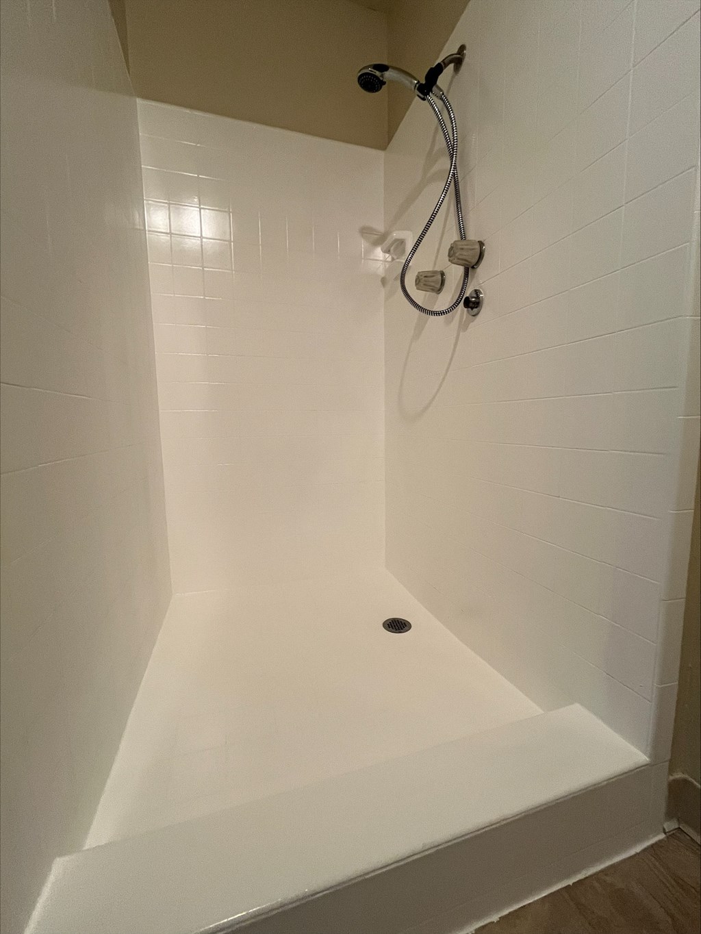 a shower with a shower head in a white shower stall