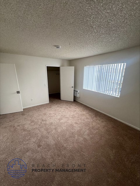 an empty room with a door to a closet and a window
