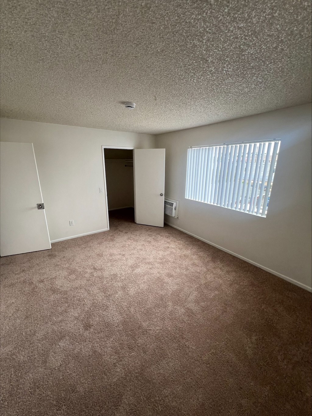 an empty room with a door to a closet and a window