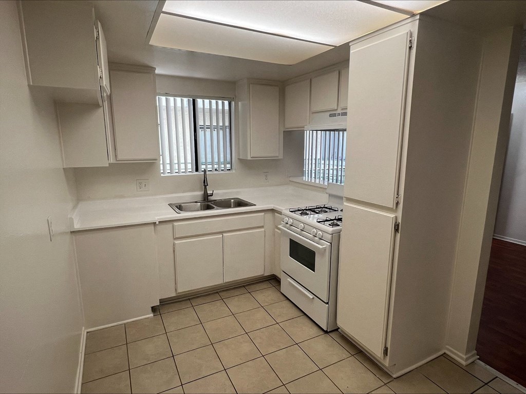 a kitchen with white cabinets and a sink and a refrigerator