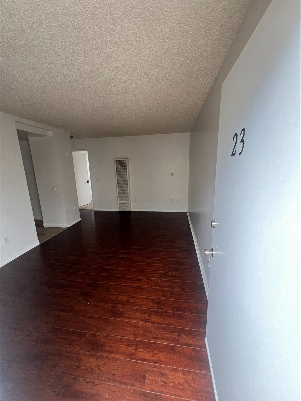 an empty living room with wood floors and white walls