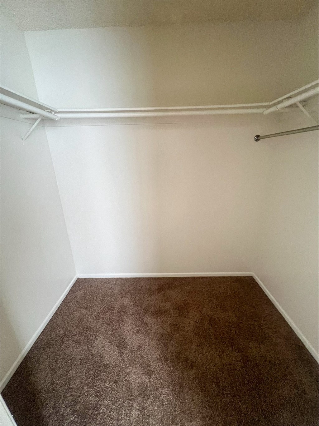 an empty room with a brown carpet and a white wall