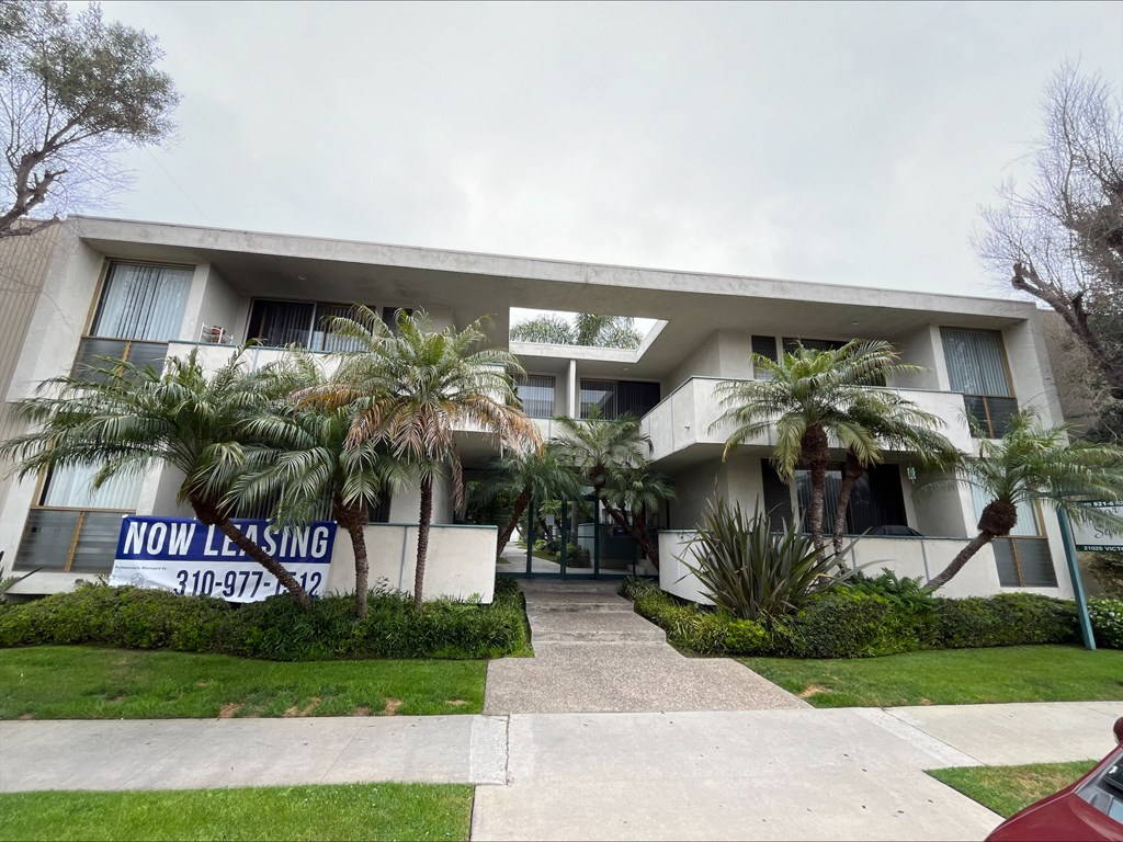 the front of a white house with palm trees in front of it