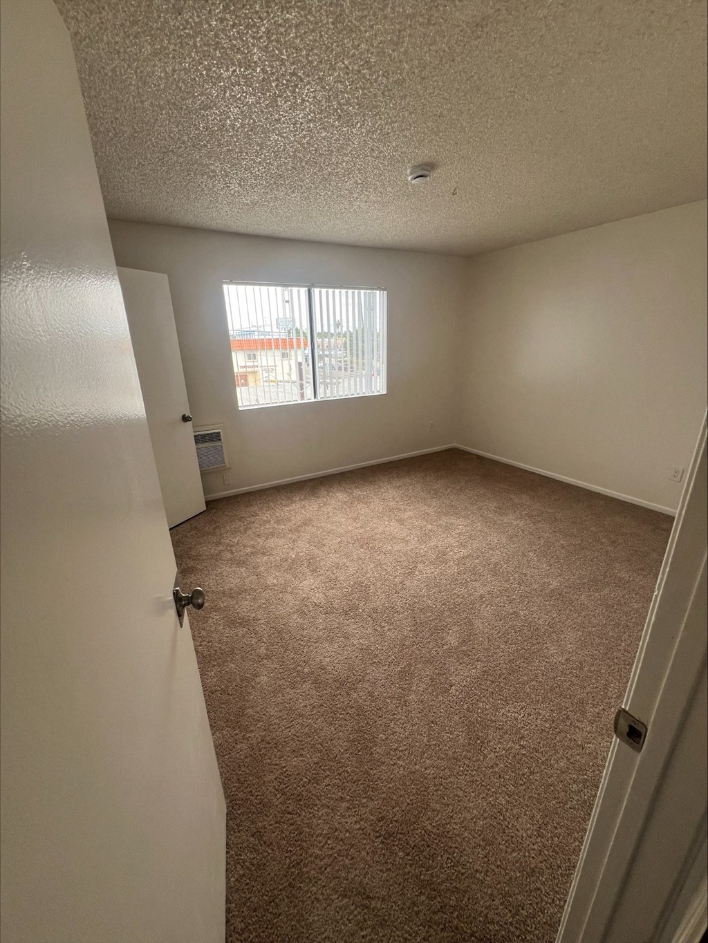 an empty bedroom with carpet and a window
