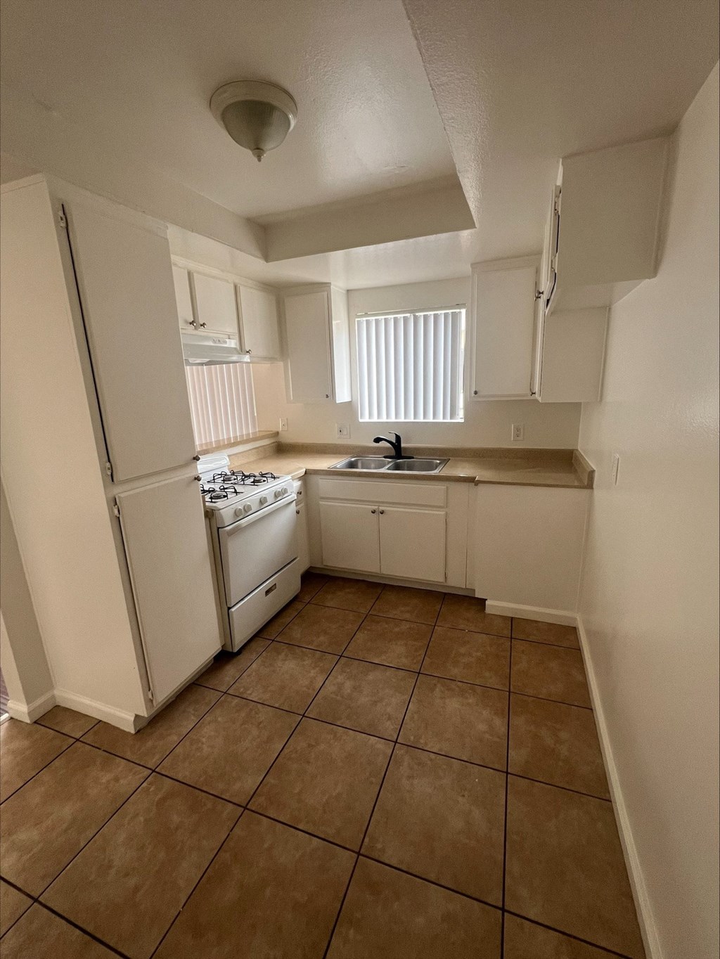 an empty kitchen with a sink and a refrigerator