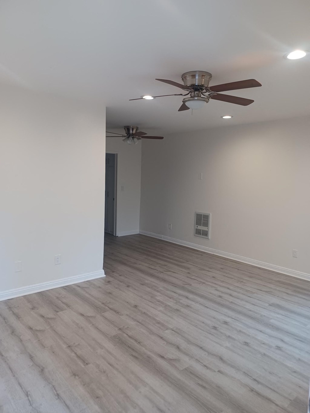 an empty living room with a ceiling fan