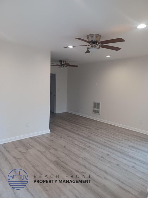 a living room with white walls and a ceiling fan