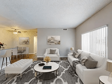 A living room with a white couch, a coffee table, and a rug.