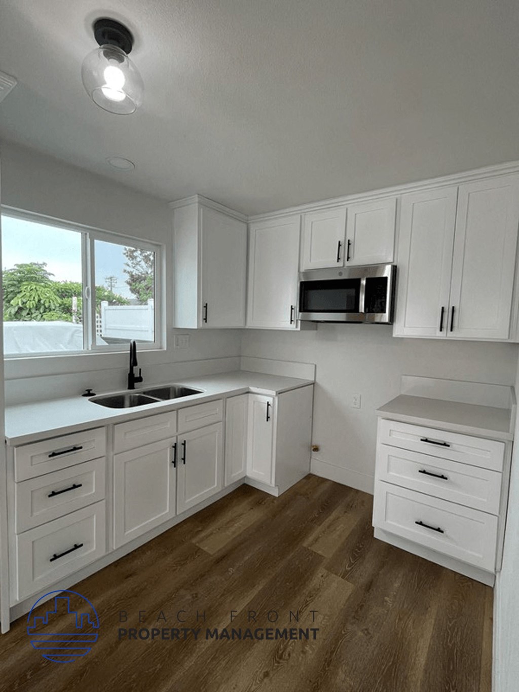 an image of a kitchen with white cabinets and a window