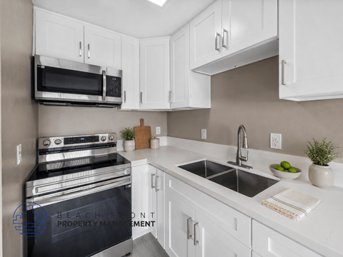 A modern kitchen with white cabinets and a black stove top oven.