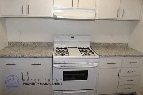 a kitchen with a stove and white cabinets