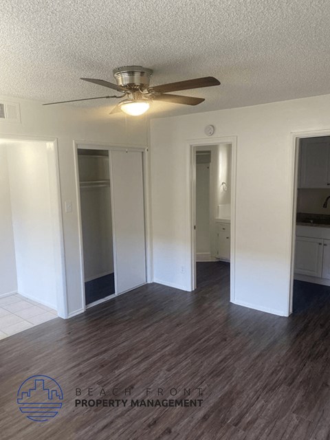 an empty living room with wood floors and a ceiling fan