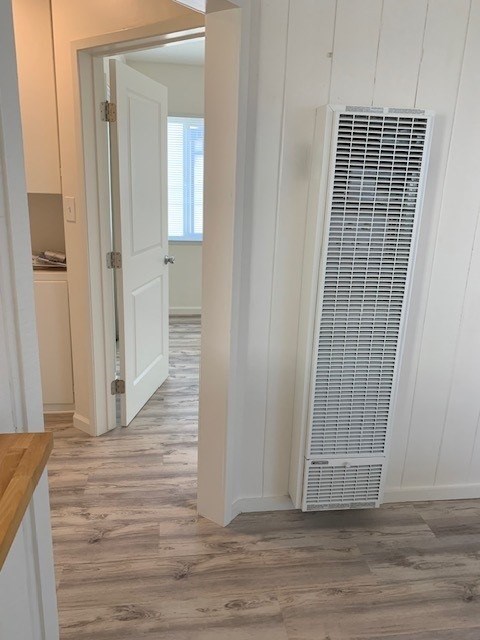 A white air conditioner is on the wall in a room with wood flooring.