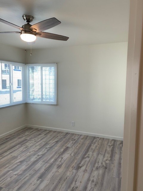 A room with a ceiling fan and a window with blinds.