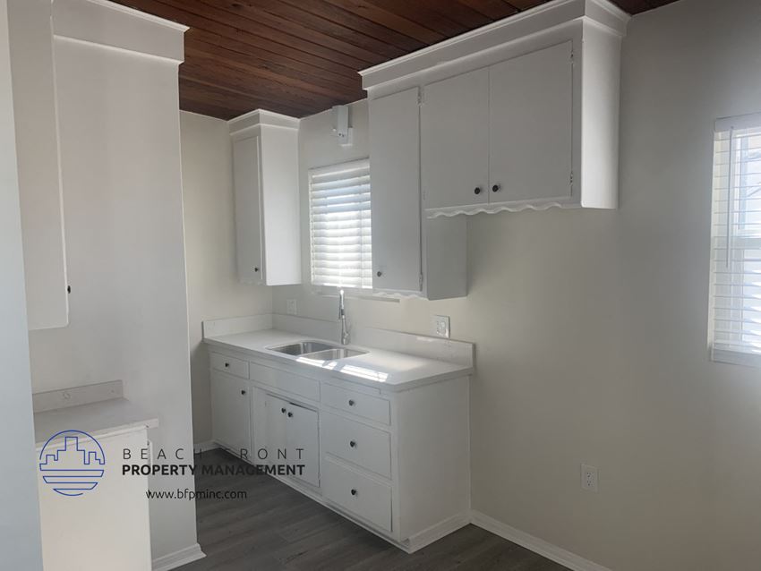 a white kitchen with white cabinets and a sink