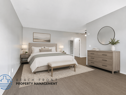 A well-lit bedroom with a large bed, a side table with a lamp, and a dresser with a mirror.