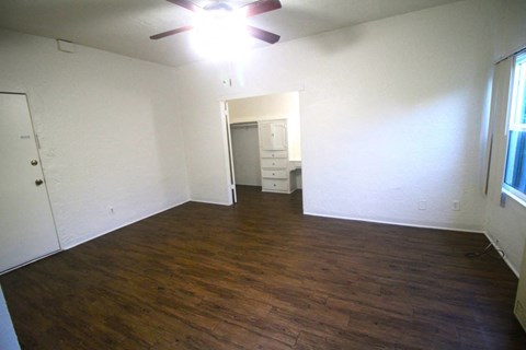 an empty living room with wood floors and a ceiling fan